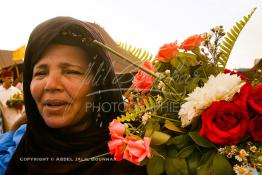 Image du Maroc Professionnelle de  Une femme du Sahara ravie d'avoir pu récupéré un bouquet de fleur durant le grand Moussem de Tan Tan. Chaque année la majorité des tribus et des grandes familles nomades du désert se retrouvent sur un site désertique pour célébrer ce grand Moussem où  danse, chants, course de chameaux et fantasia font partie des festivités. , Samedi 18 septembre 2004, ((Photo / Abdeljalil Bounhar)